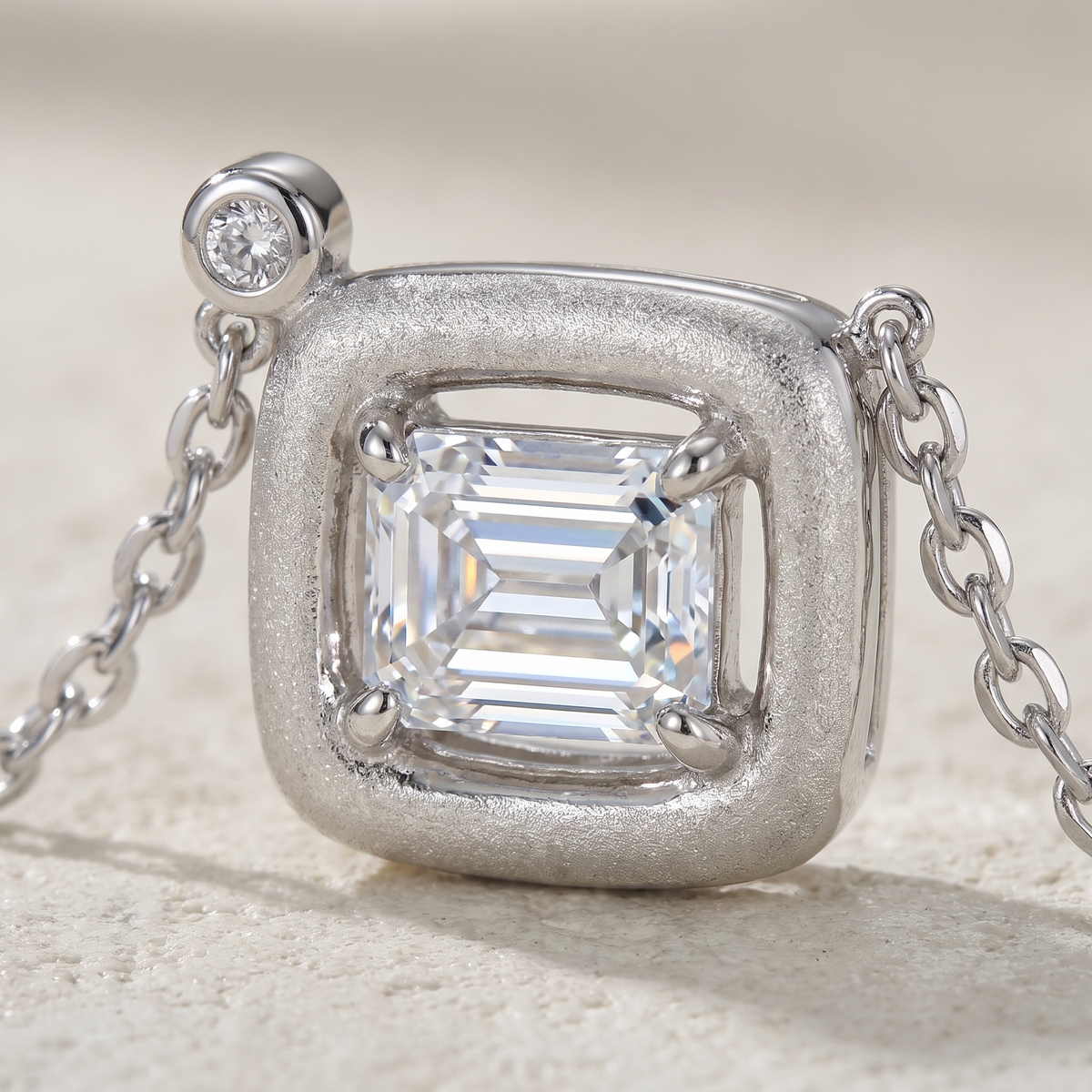 Close-up of Marhabu emerald-cut moissanite in frosted square S925 pendant